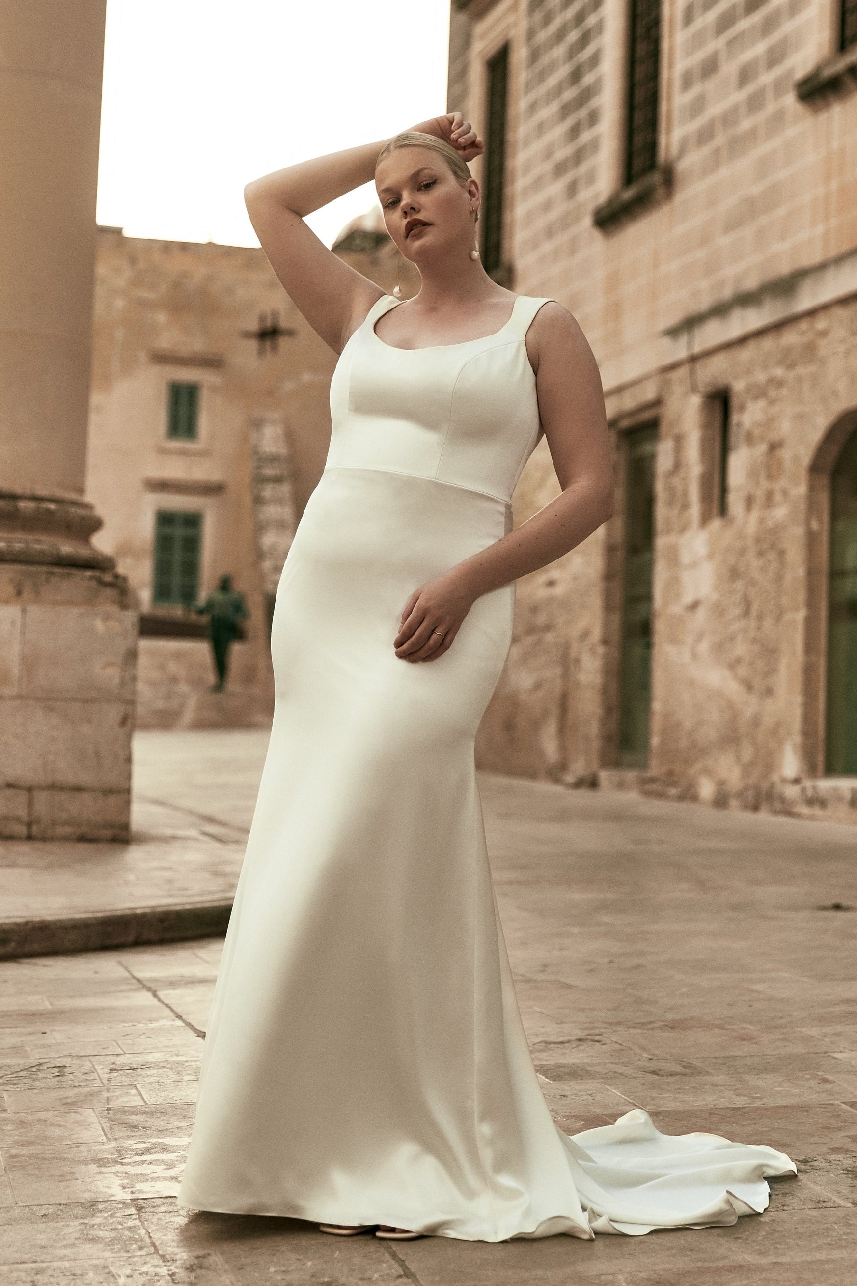 Adrian : A sleek wedding gown with a low scoopneck, curved straps, and buttons
