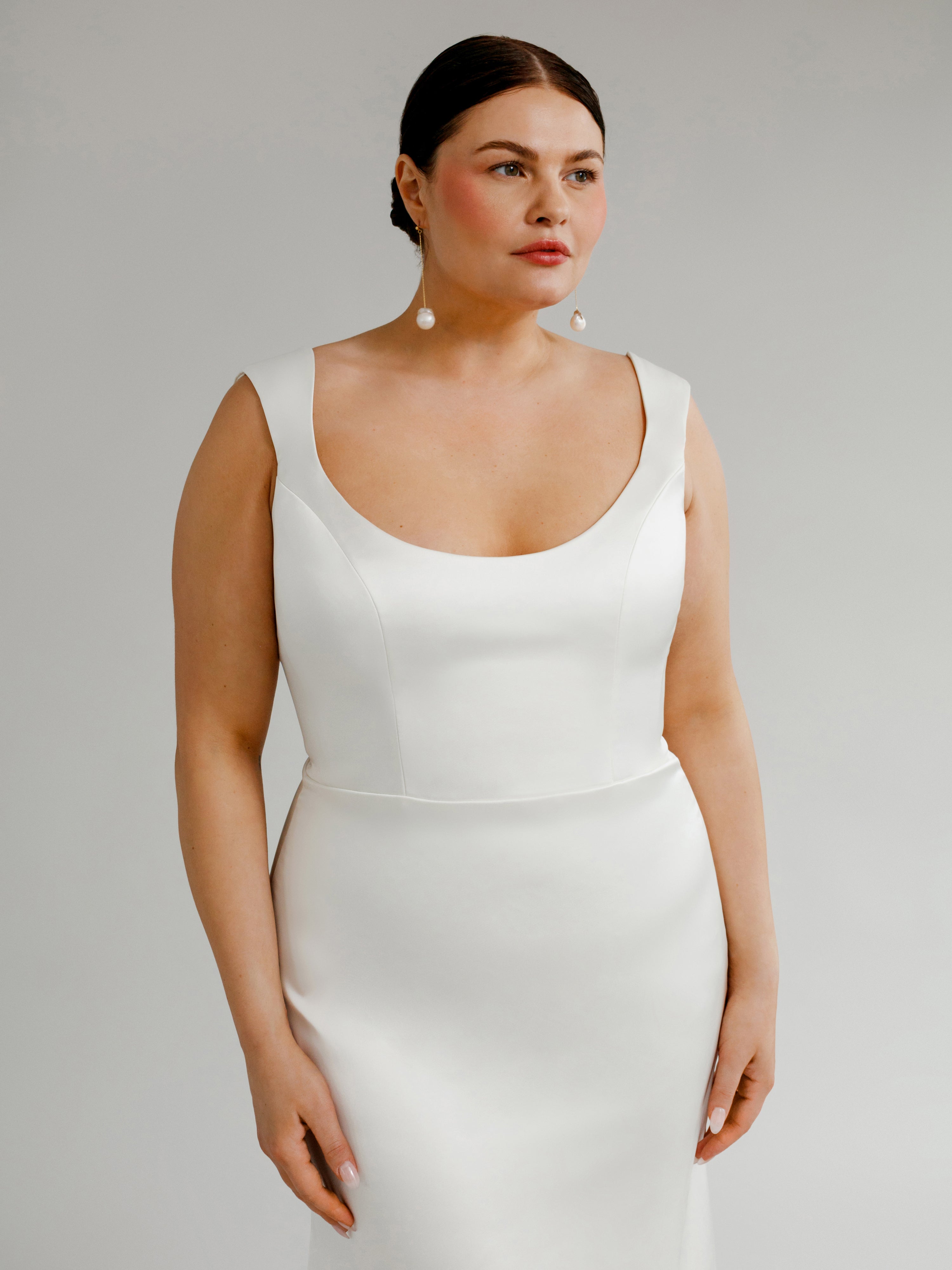 Adrian : A sleek wedding gown with a low scoopneck, curved straps, and buttons
